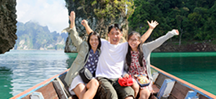Man sitting in between wife and daughter on boat in lake all smiling with open arms in air