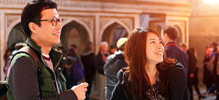 a man and woman smilling while looking up  at something while touring a building