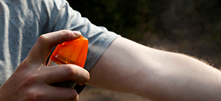 man sparying bug repelent on arm