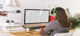 woman with headphones sitting at desk using a computer