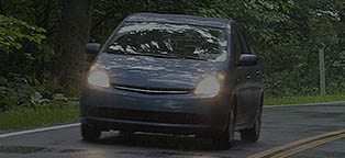 hybrid car driving on tree lined road