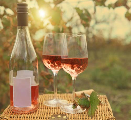 Bottle of wine and two glasses on top of picnic basket