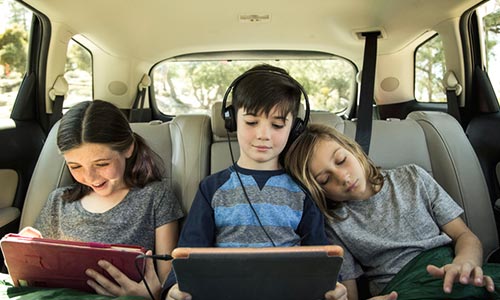 kids on ipads in the backseat of a car