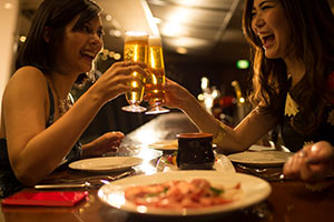 two women toasting glasses at dinner