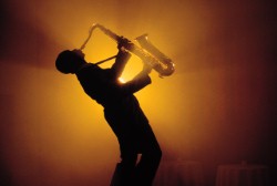 saxophone player playing in an orange light