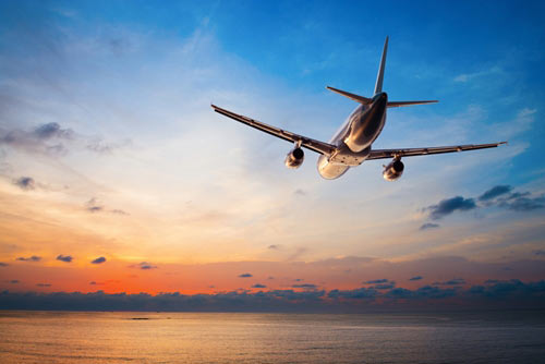 airliner crusing over ocean at sunset